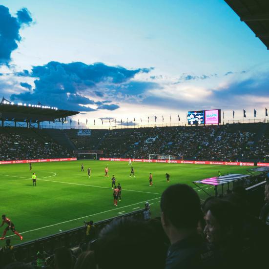 Fodboldbane med spillere i aftenlys