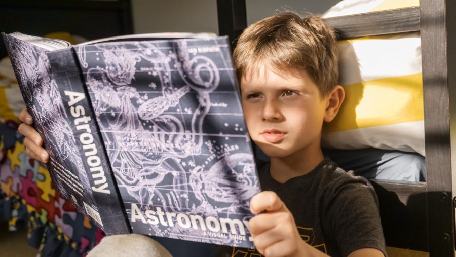 dreng der læser i en bog om astronomi